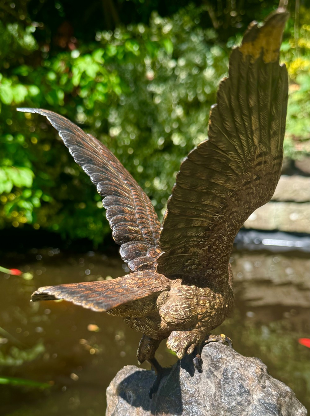 A cold-painted bronze sculpture depicting a hawk with open wings perched atop a natural quartz stone base. View XXVIII