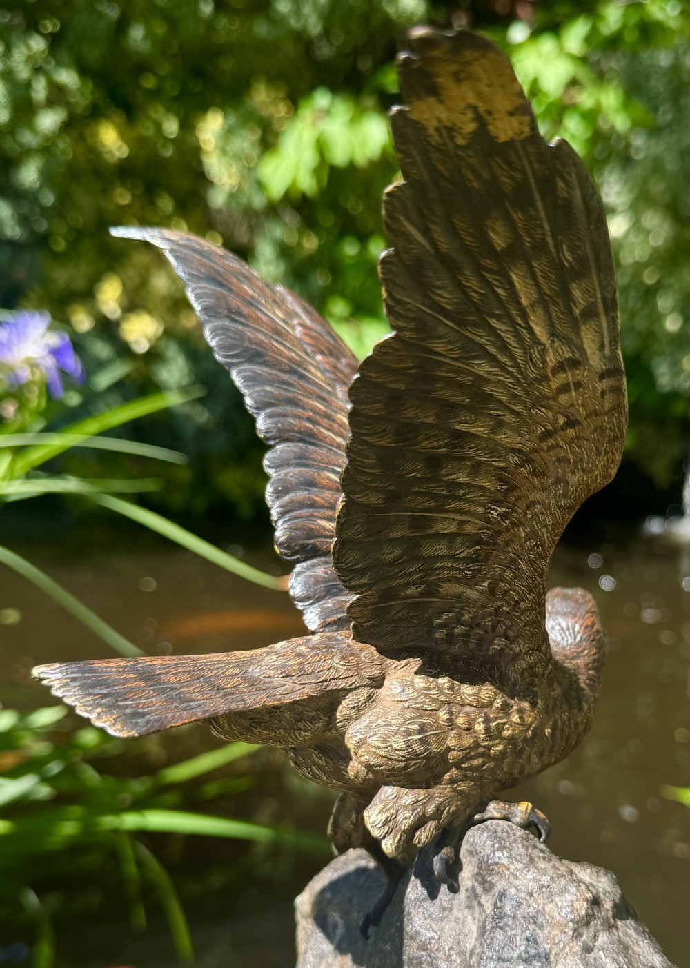 A cold-painted bronze sculpture depicting a hawk with open wings perched atop a natural quartz stone base. View XXIX