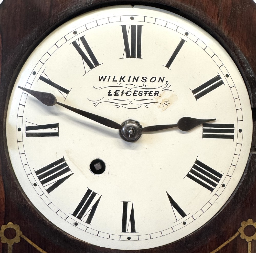 A dark mahogany lancet top mantel clock featuring brass inlay motifs, a circular white dial with Roman numerals, side ring handles, and brass ball feet. View IV