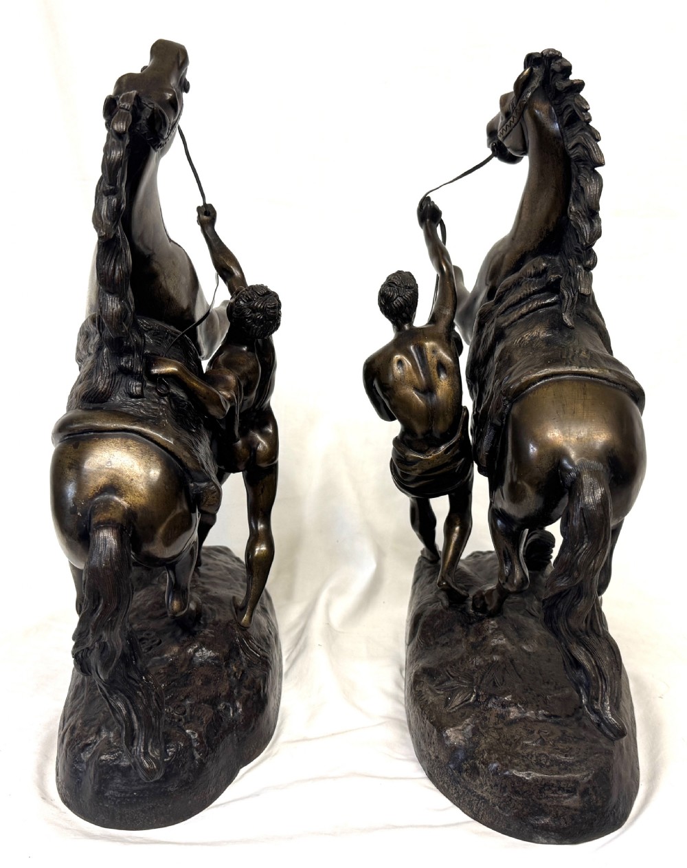 A pair of dark patinated bronze equestrian sculptures depicting rearing horses restrained by grooms on naturalistic rockwork bases. View VIII