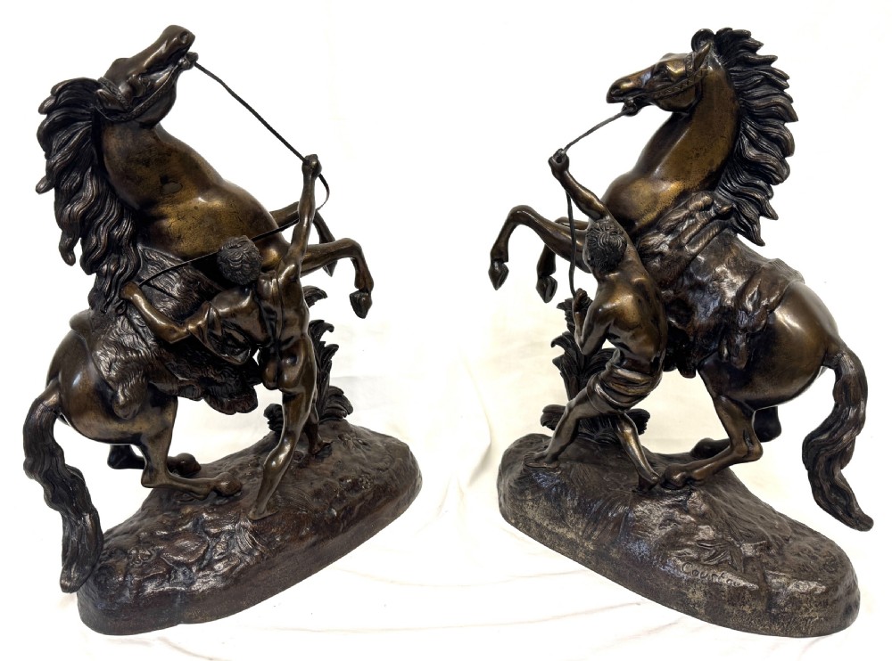 A pair of dark patinated bronze equestrian sculptures depicting rearing horses restrained by grooms on naturalistic rockwork bases. View IX