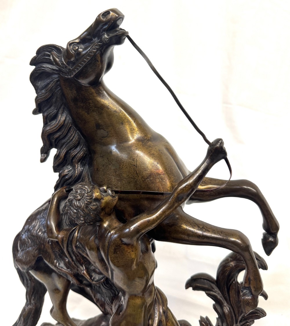 A pair of dark patinated bronze equestrian sculptures depicting rearing horses restrained by grooms on naturalistic rockwork bases. View XI