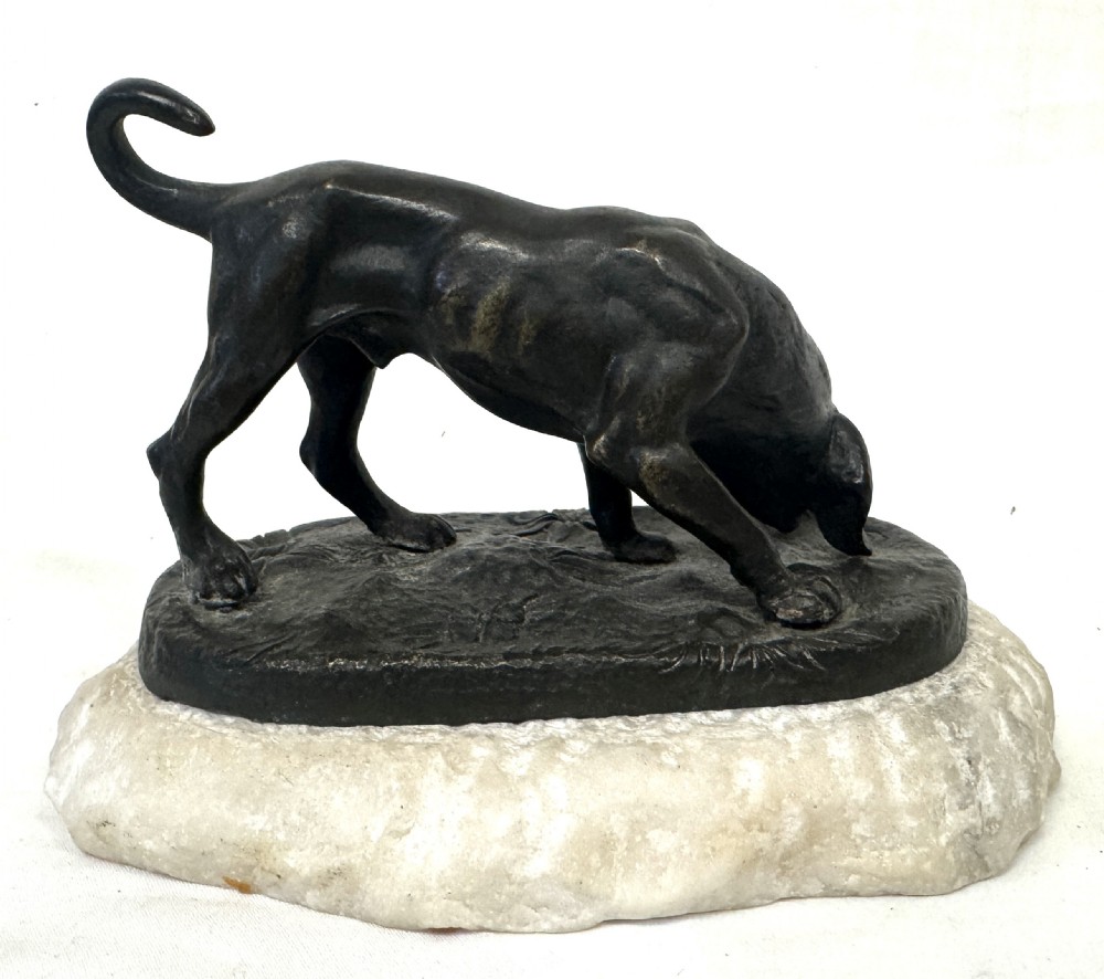 A dark patinated bronze sculpture depicting a hunting hound scenting the ground, mounted on a carved white marble base. View III