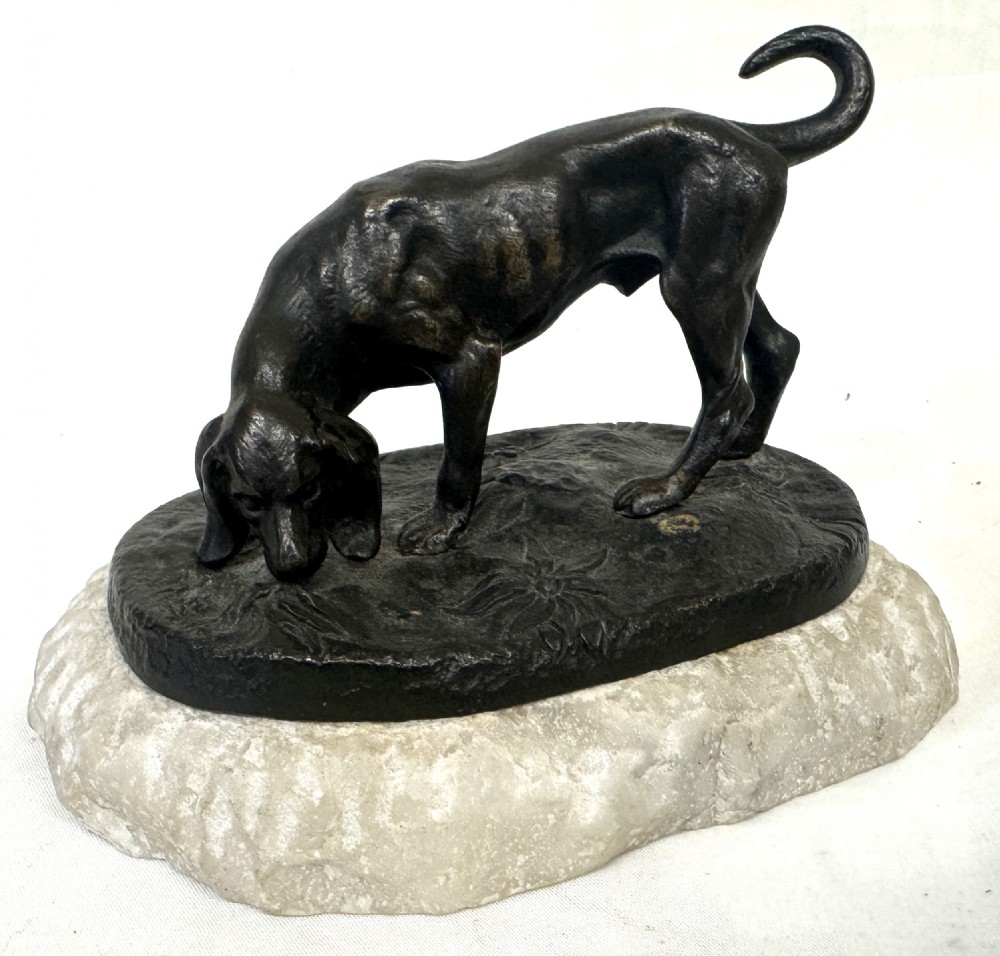 A dark patinated bronze sculpture depicting a hunting hound scenting the ground, mounted on a carved white marble base. View IV