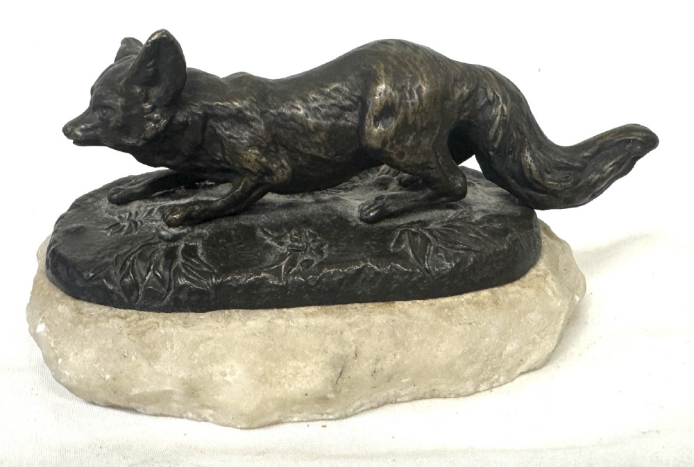An antique dark bronze sculpture of a prowling fox set upon a naturalistic metal mound atop a cream marble base. View II