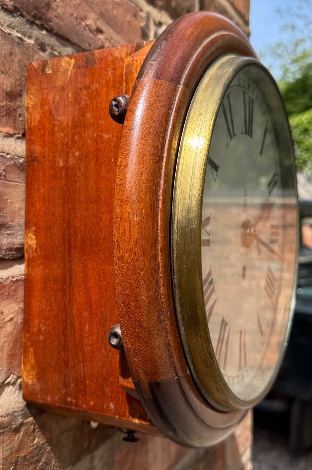 A circular antique mahogany wall clock with a brass bezel and an off-white dial marked with Roman numerals and the GPO stamp. View VII
