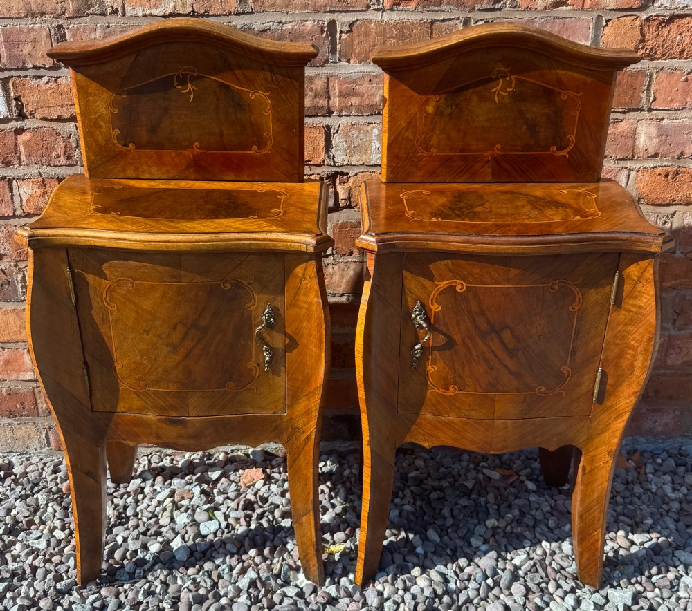 A pair of antique inlaid satinwood bedside cabinets featuring curved sides, decorative marquetry, shaped top galleries, and single doors with ornate brass handles.