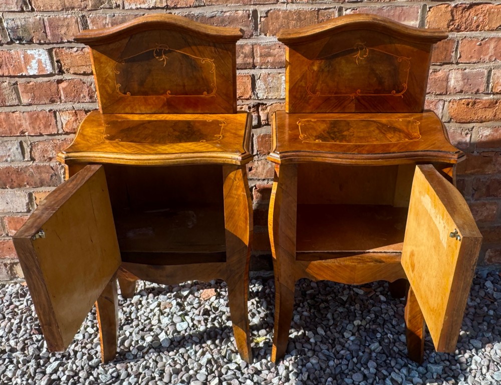 A pair of antique inlaid satinwood bedside cabinets featuring curved sides, decorative marquetry, shaped top galleries, and single doors with ornate brass handles. View II