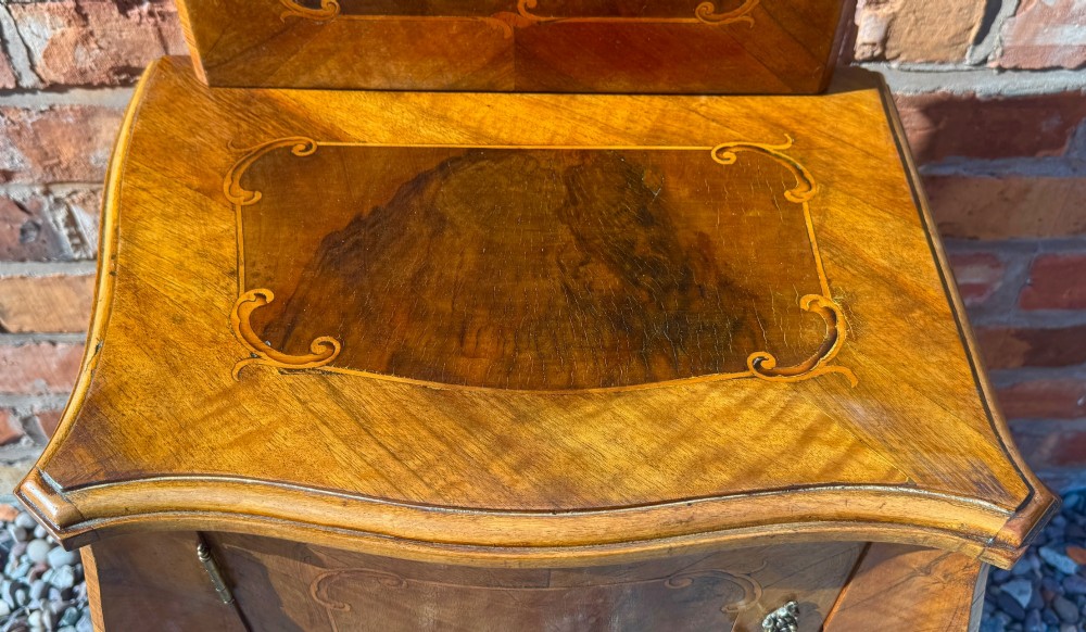 A pair of antique inlaid satinwood bedside cabinets featuring curved sides, decorative marquetry, shaped top galleries, and single doors with ornate brass handles. View V