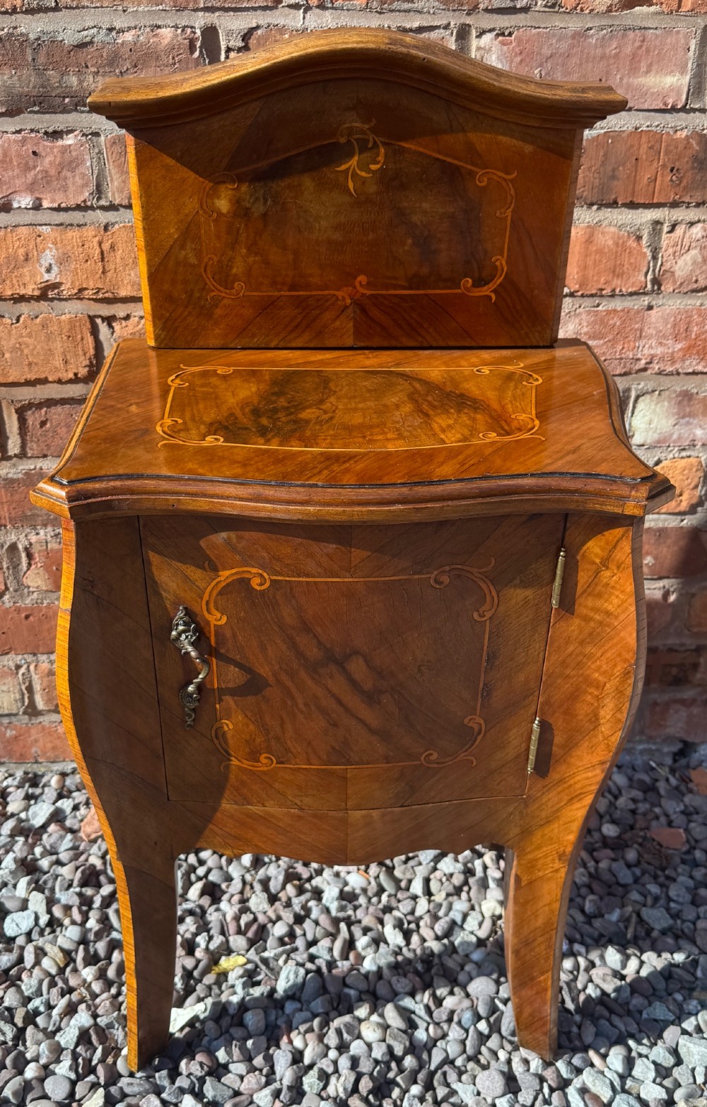 A pair of antique inlaid satinwood bedside cabinets featuring curved sides, decorative marquetry, shaped top galleries, and single doors with ornate brass handles. View X