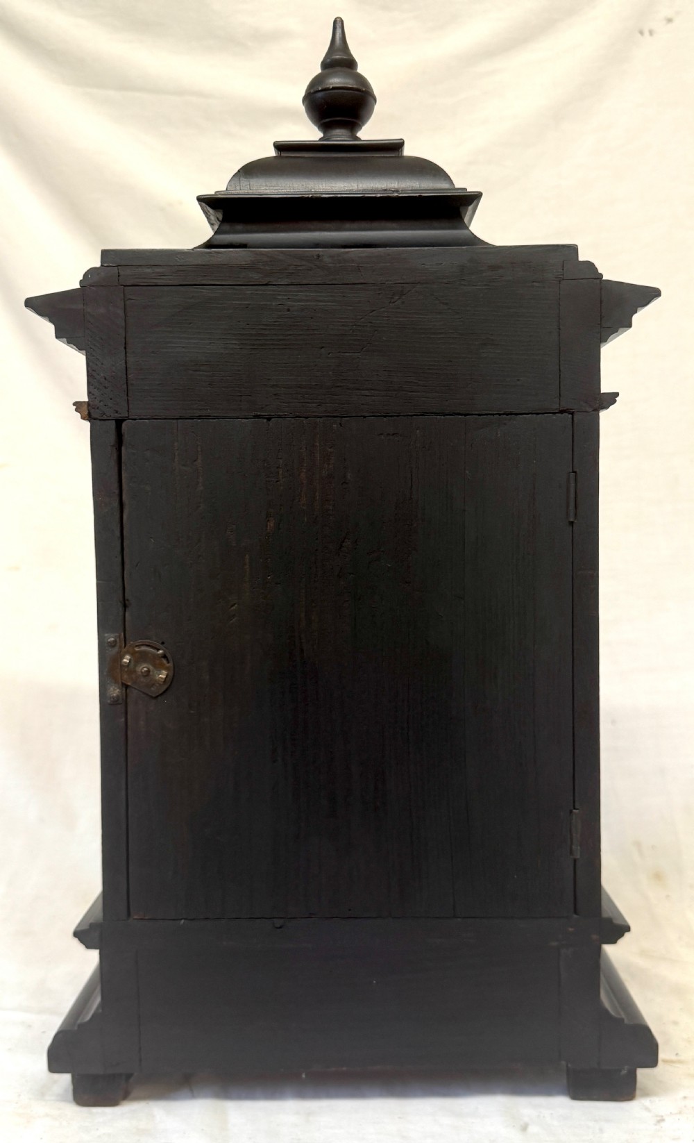 An ebonised wooden mantel clock featuring a stepped pedestal base, turned finial, and an engraved silvered metal dial with Roman numerals. View VII