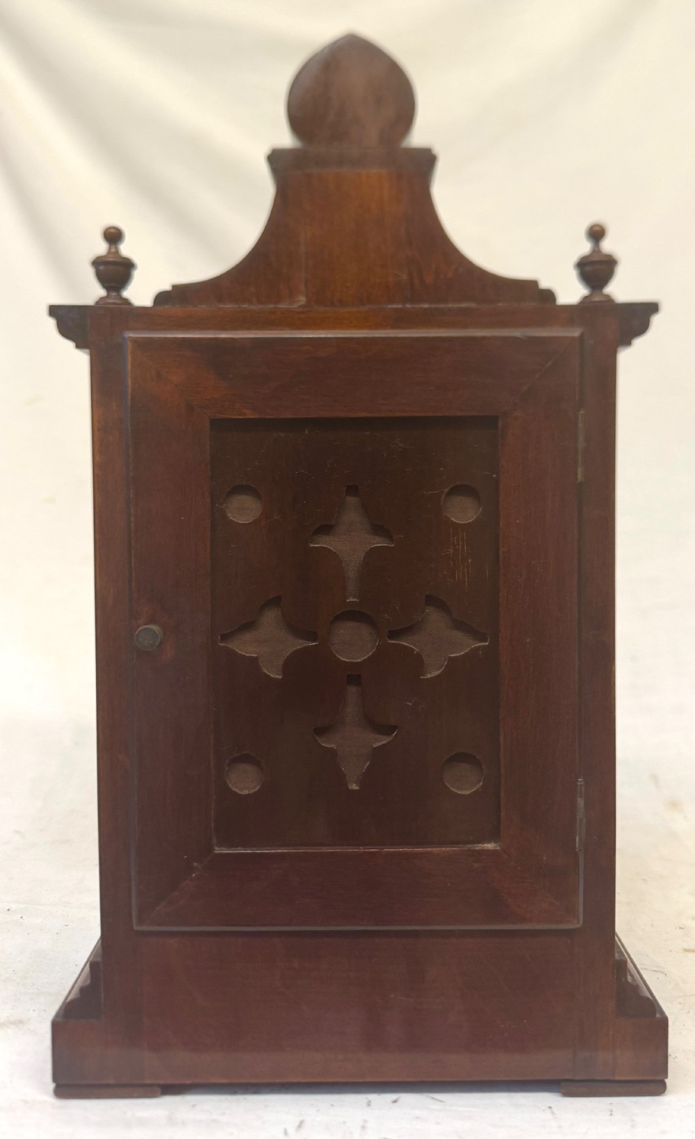 An antique walnut bracket clock featuring an arched brass dial with decorative corner spandrels, Roman numerals, and turned finials on a stepped wood base. View VII