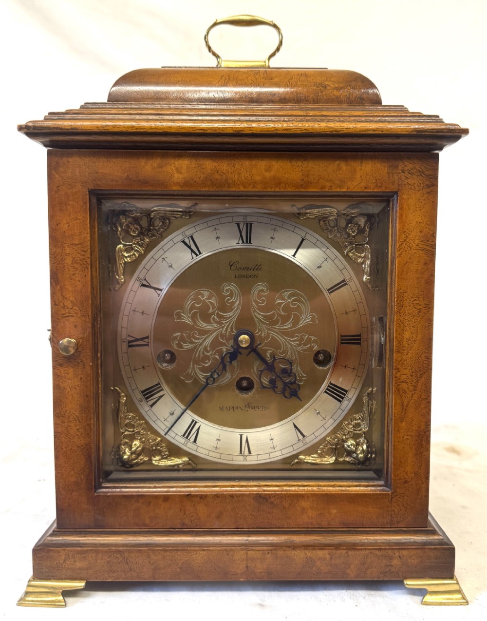 A burr walnut basket top mantel clock featuring an etched brass dial with Roman numerals, corner spandrels, side glass panels, and a top brass handle. View II
