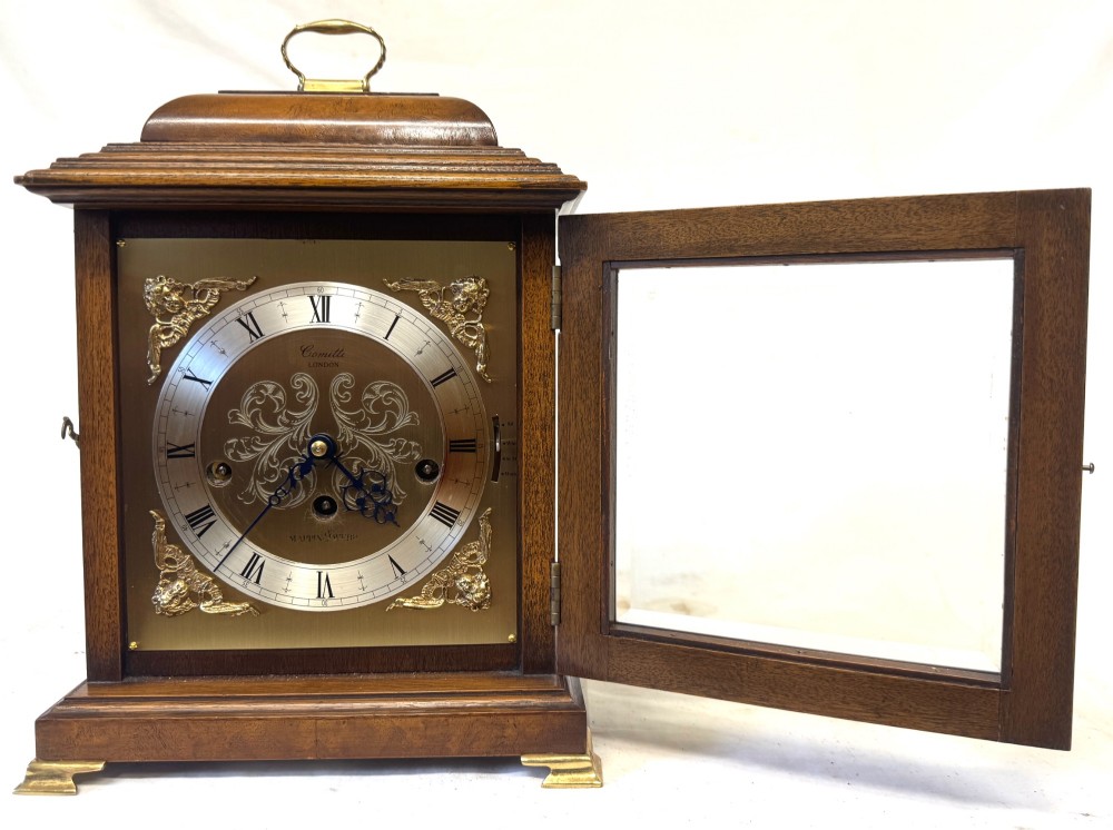 A burr walnut basket top mantel clock featuring an etched brass dial with Roman numerals, corner spandrels, side glass panels, and a top brass handle. View III