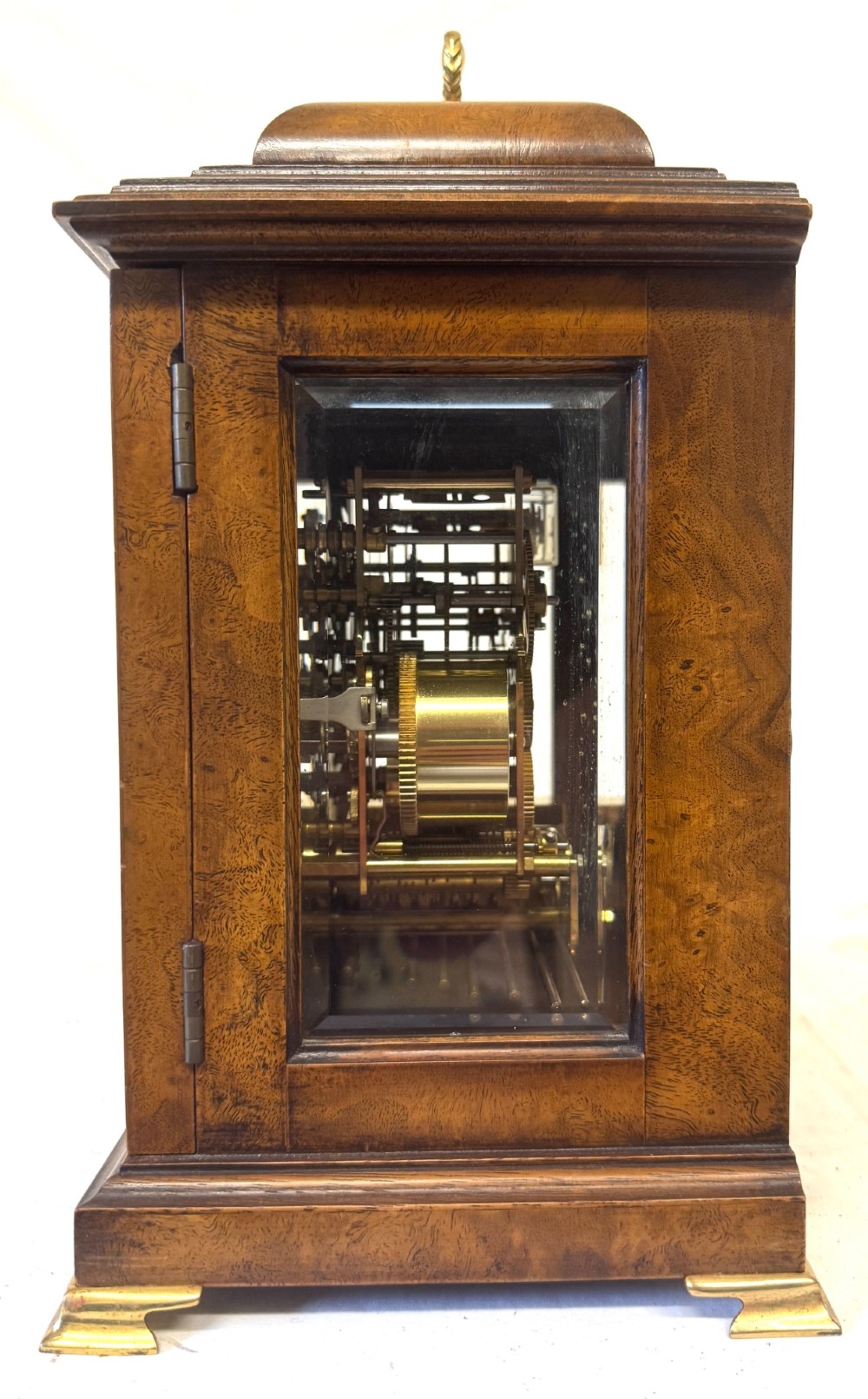 A burr walnut basket top mantel clock featuring an etched brass dial with Roman numerals, corner spandrels, side glass panels, and a top brass handle. View VI