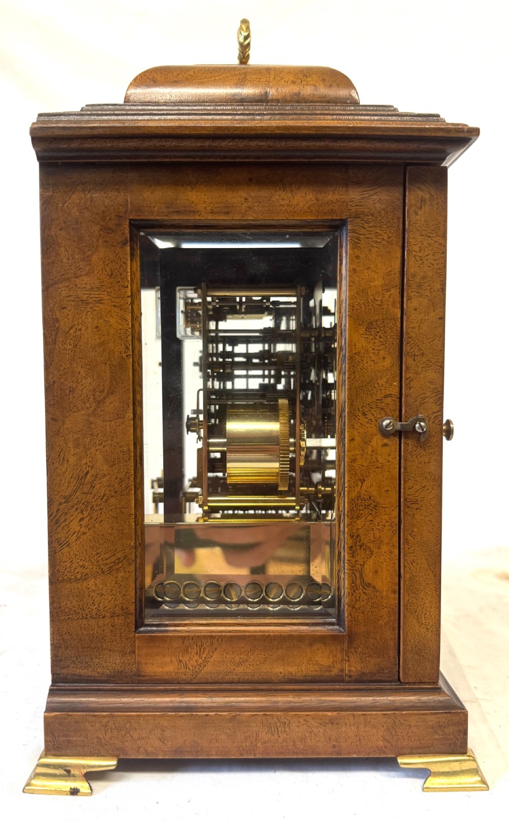 A burr walnut basket top mantel clock featuring an etched brass dial with Roman numerals, corner spandrels, side glass panels, and a top brass handle. View VII