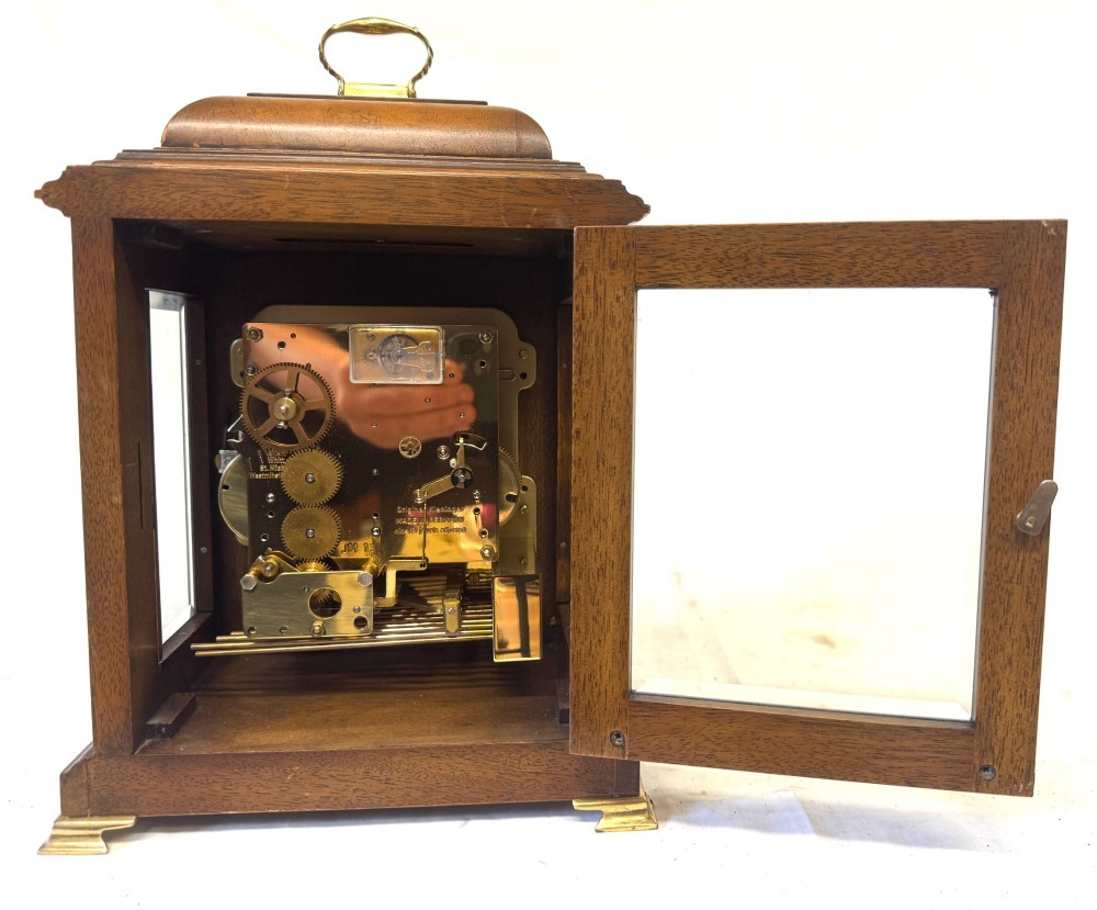 A burr walnut basket top mantel clock featuring an etched brass dial with Roman numerals, corner spandrels, side glass panels, and a top brass handle. View IX