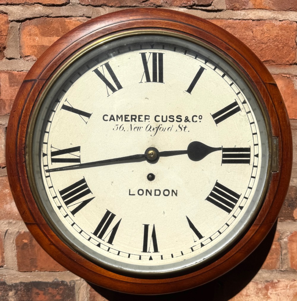 A circular Victorian mahogany wall clock with a cream painted dial displaying Roman numerals, makers inscription for Camerer Cuss & Co London, and a brass bezel. View III