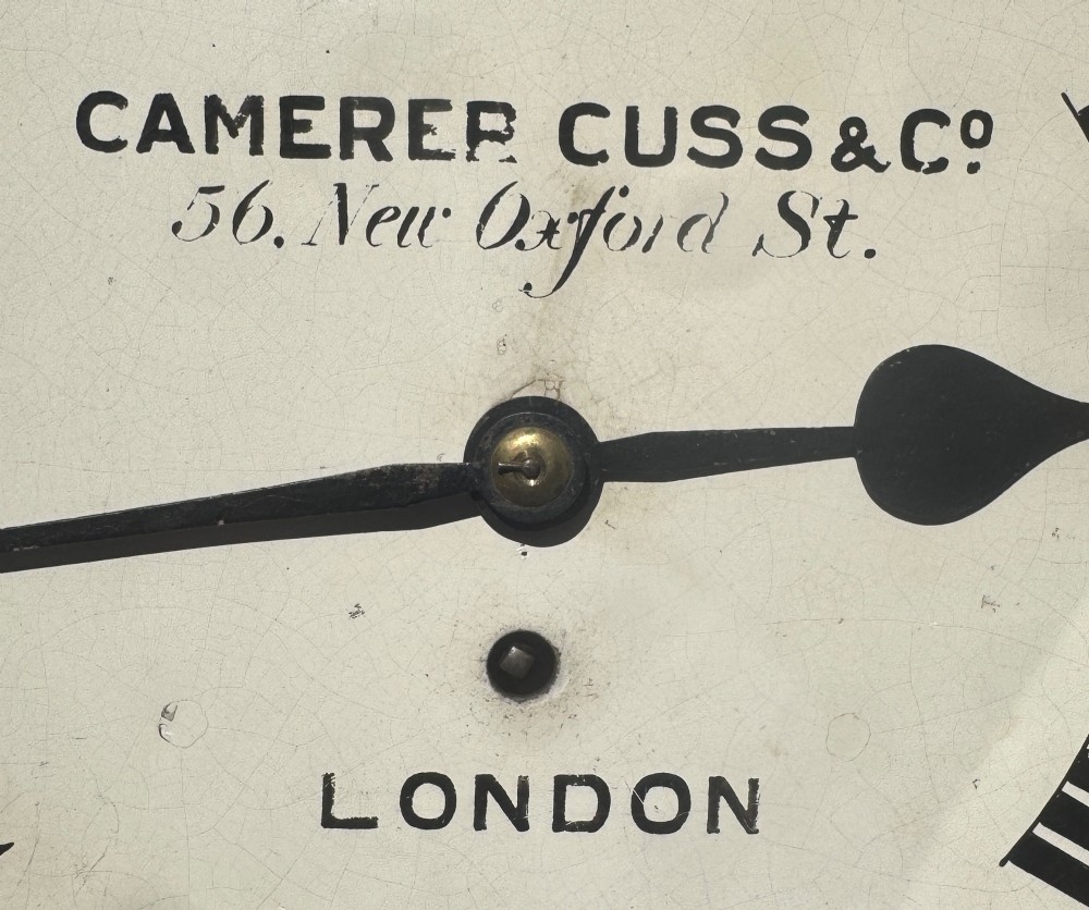A circular Victorian mahogany wall clock with a cream painted dial displaying Roman numerals, makers inscription for Camerer Cuss & Co London, and a brass bezel. View V