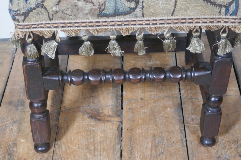 A pair of 17th-century oak back stools upholstered in tapestry fabric with tassel trim and turned legs. View IX