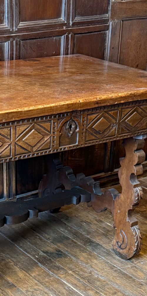 A 17th-century dark walnut side table featuring a geometrically carved single drawer, detailed trestle end supports, and a shaped central stretcher. View VI