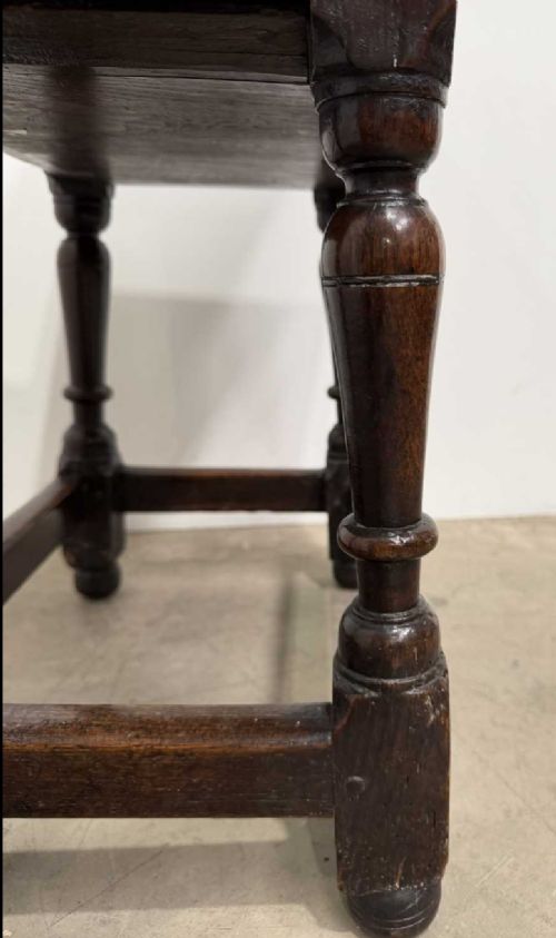 A 17th-century dark oak joint stool featuring a carved arcade frieze, turned legs, and sturdy base stretchers. View VII