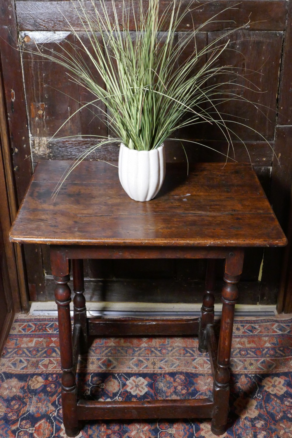 A 17th-century dark oak side table featuring a rectangular plank top, turned legs, and square perimeter stretchers.