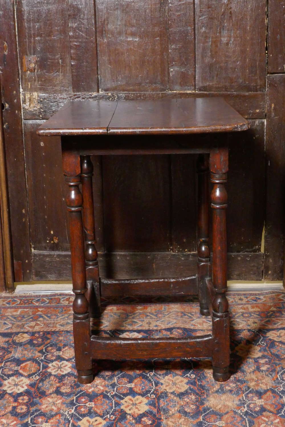 A 17th-century dark oak side table featuring a rectangular plank top, turned legs, and square perimeter stretchers. View V