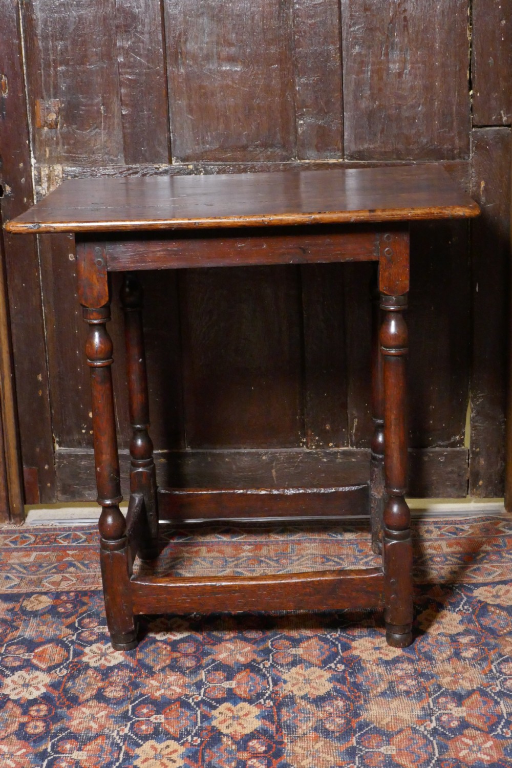 A 17th-century dark oak side table featuring a rectangular plank top, turned legs, and square perimeter stretchers. View VI