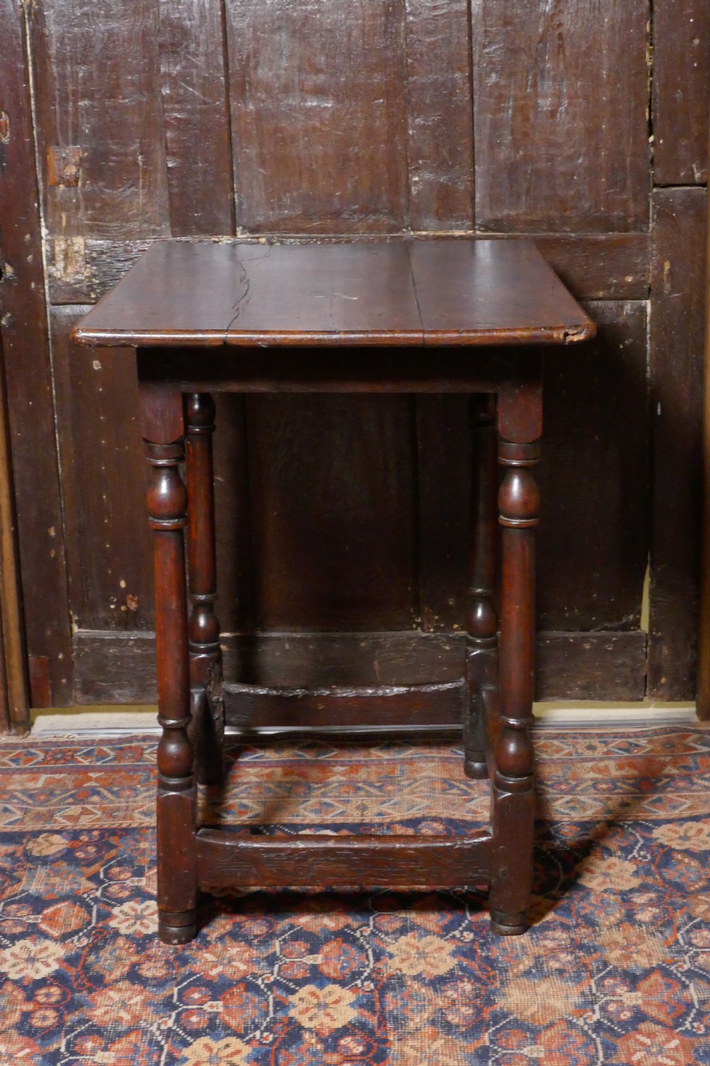 A 17th-century dark oak side table featuring a rectangular plank top, turned legs, and square perimeter stretchers. View VII