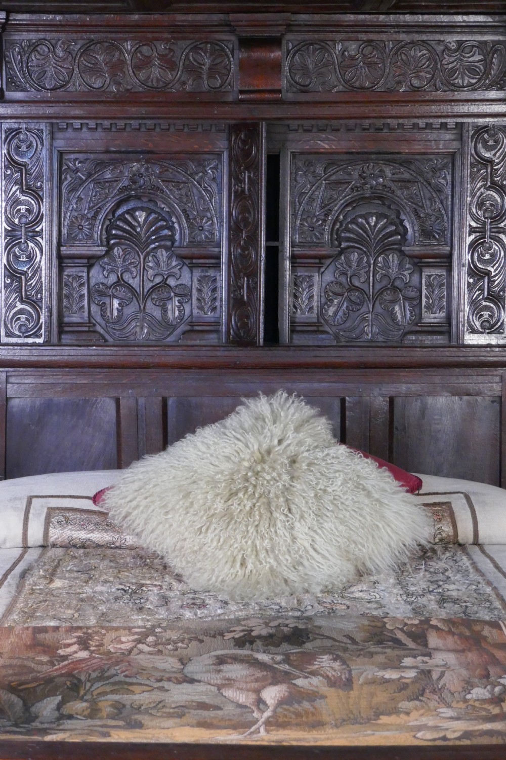 A dark oak 17th-century full tester bed featuring a relief-carved headboard, turned front posts, and a coffered ceiling canopy. View III