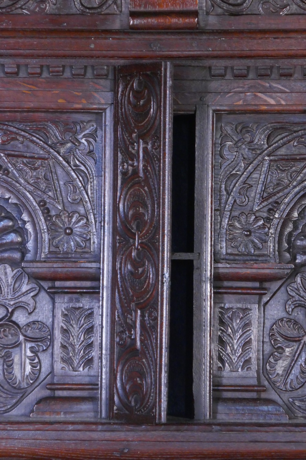A dark oak 17th-century full tester bed featuring a relief-carved headboard, turned front posts, and a coffered ceiling canopy. View V