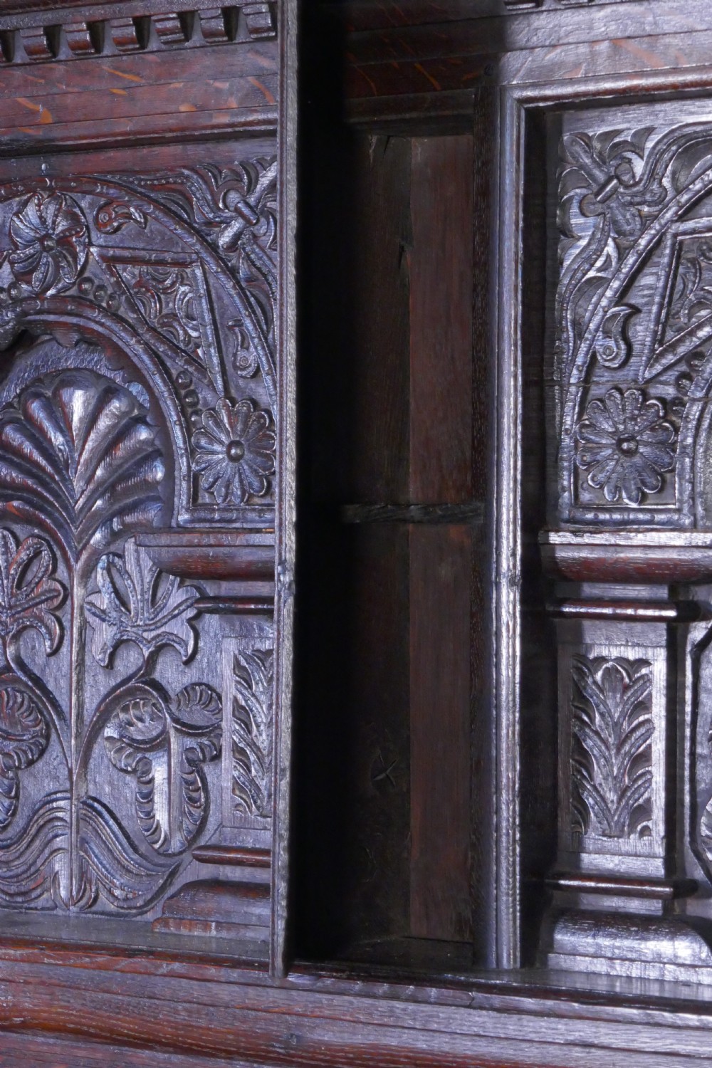 A dark oak 17th-century full tester bed featuring a relief-carved headboard, turned front posts, and a coffered ceiling canopy. View VI