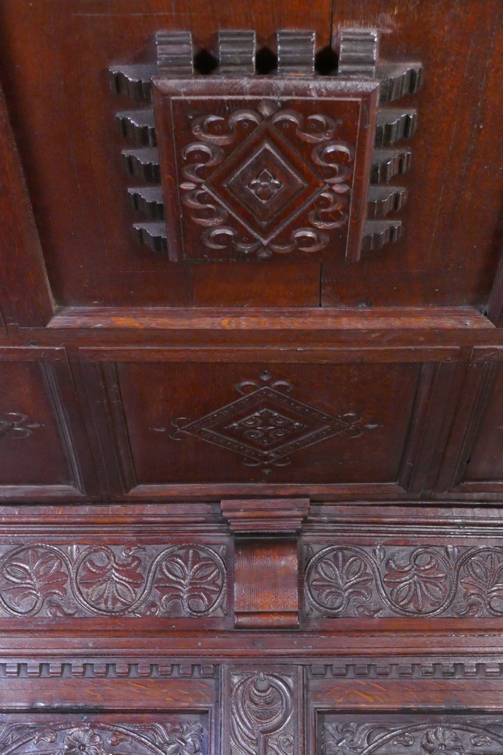 A dark oak 17th-century full tester bed featuring a relief-carved headboard, turned front posts, and a coffered ceiling canopy. View XI