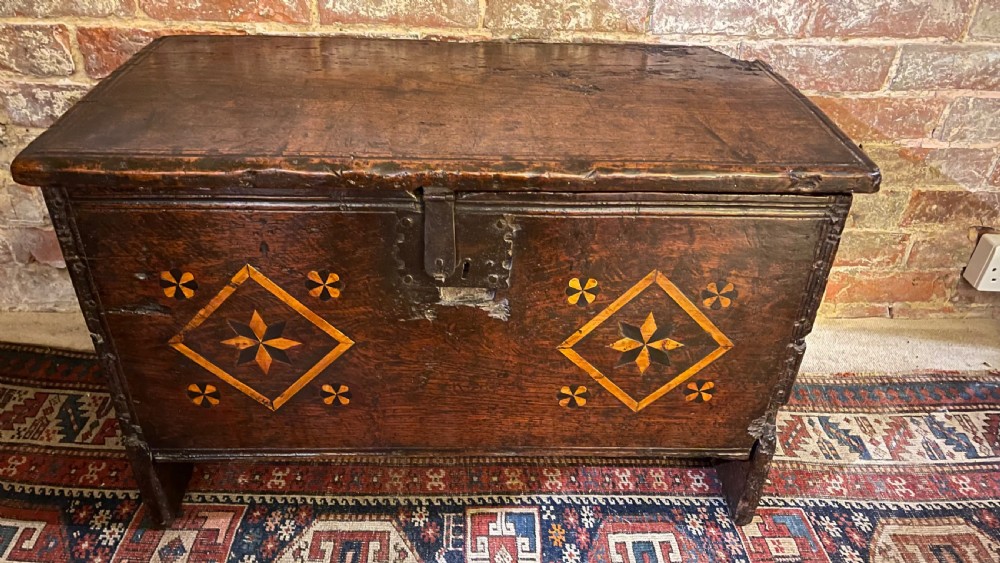 A dark oak 16th-century coffer featuring geometric star marquetry inlay within diamond panels and a hand-forged iron lockplate. View V