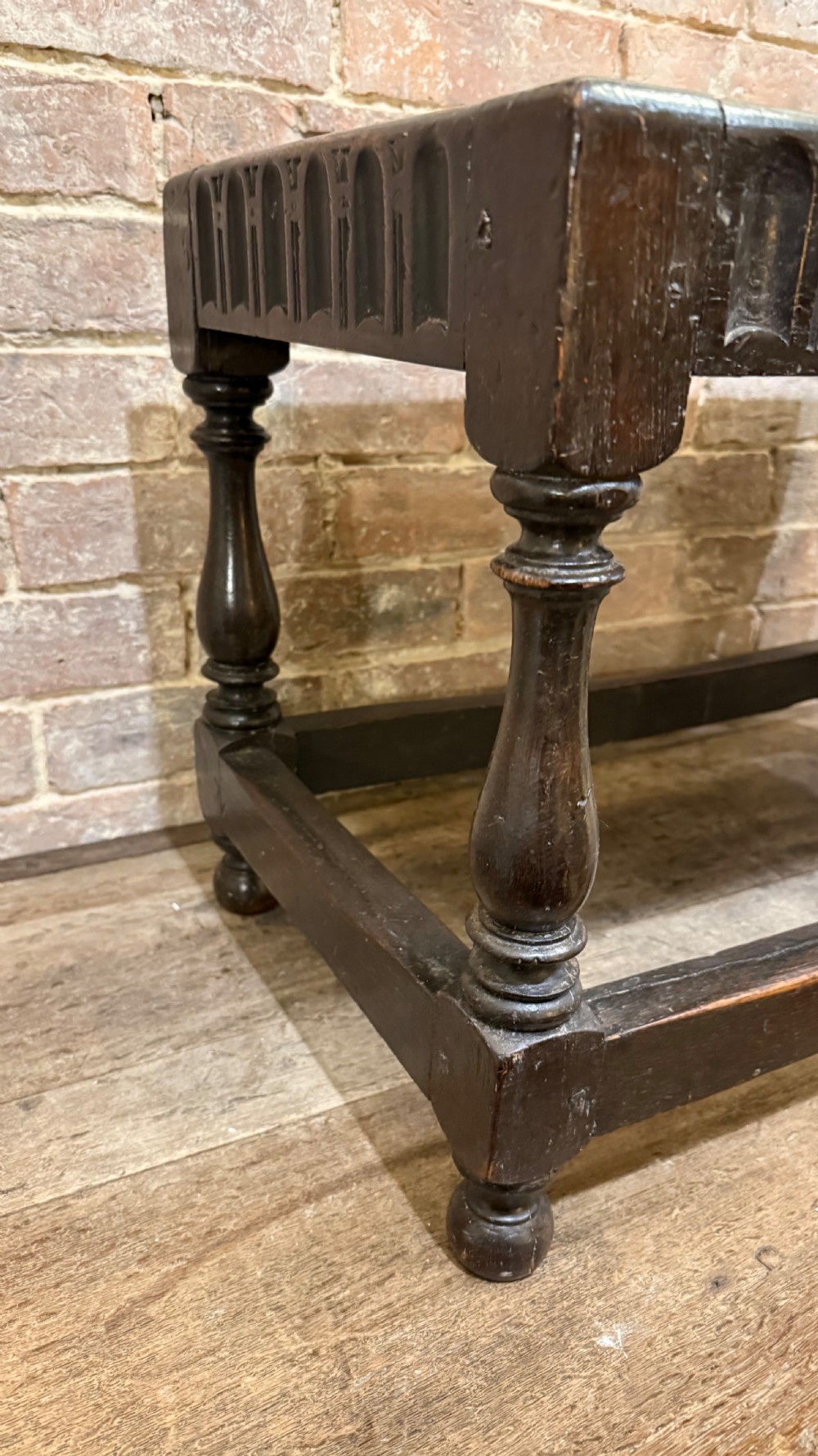 A dark oak 17th-century joint stool featuring a carved arcaded apron, turned legs, and lower box stretchers. View IV
