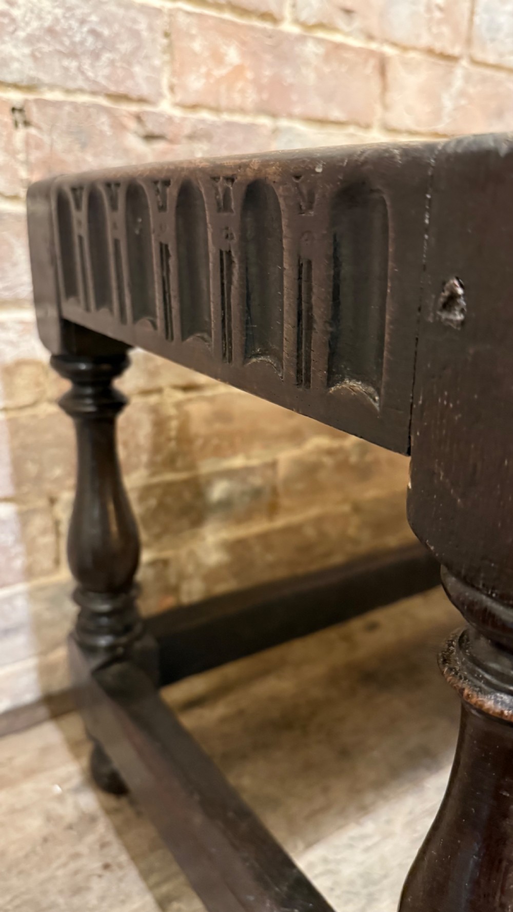 A dark oak 17th-century joint stool featuring a carved arcaded apron, turned legs, and lower box stretchers. View VI