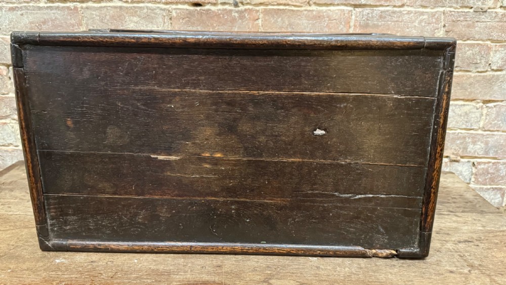A dark oak 17th-century joint stool featuring a carved arcaded apron, turned legs, and lower box stretchers. View XIX