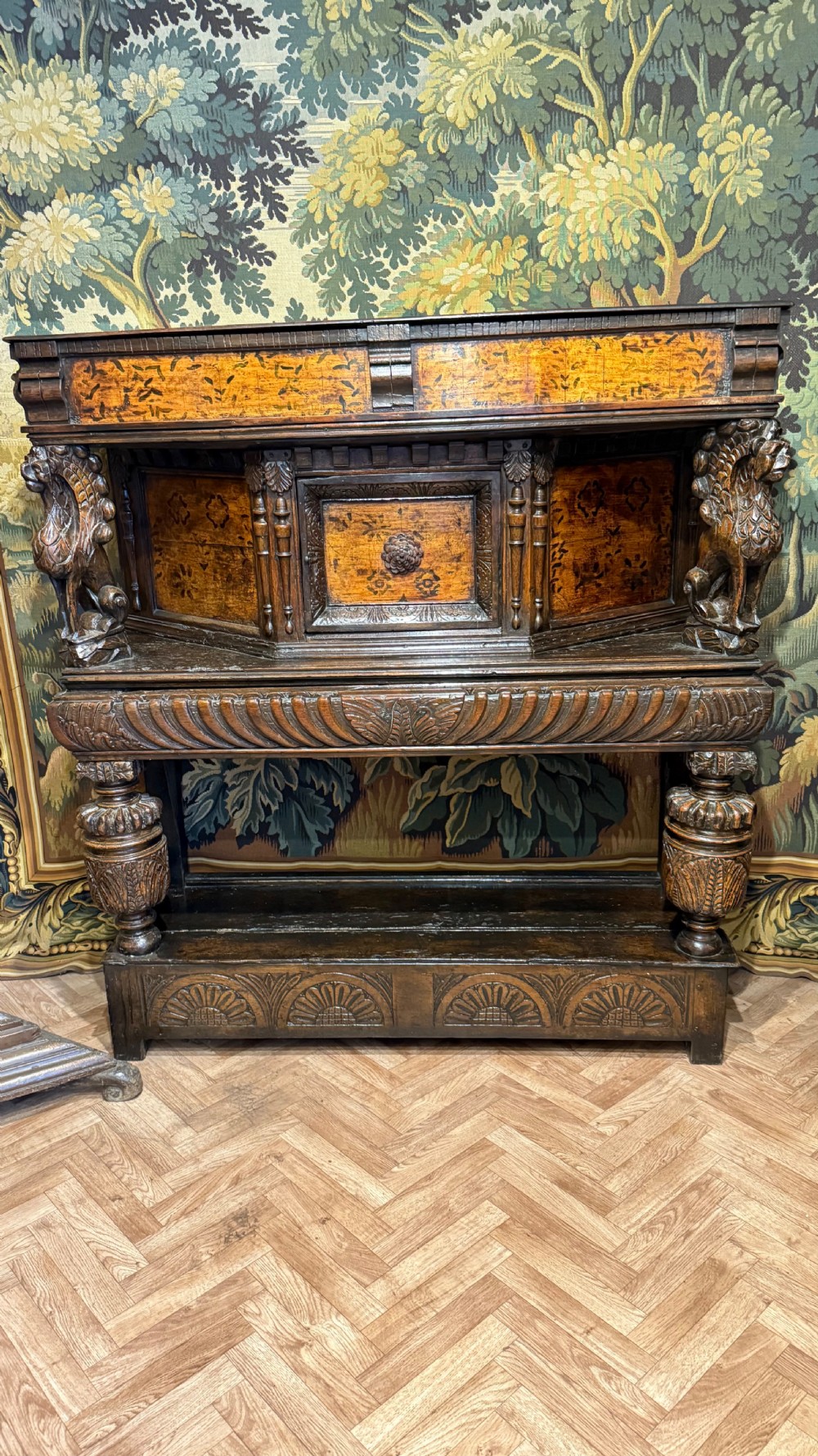 A 17th-century carved oak livery cupboard featuring inlaid wooden panels, carved lion supports, and bulbous turned legs. View III