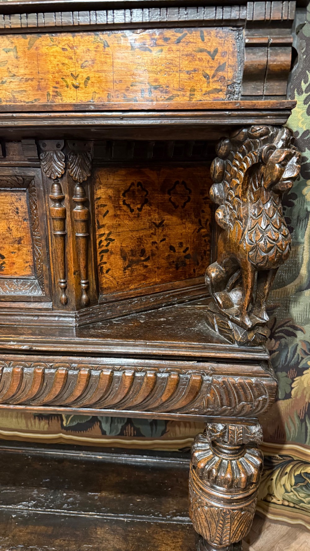 A 17th-century carved oak livery cupboard featuring inlaid wooden panels, carved lion supports, and bulbous turned legs. View VI