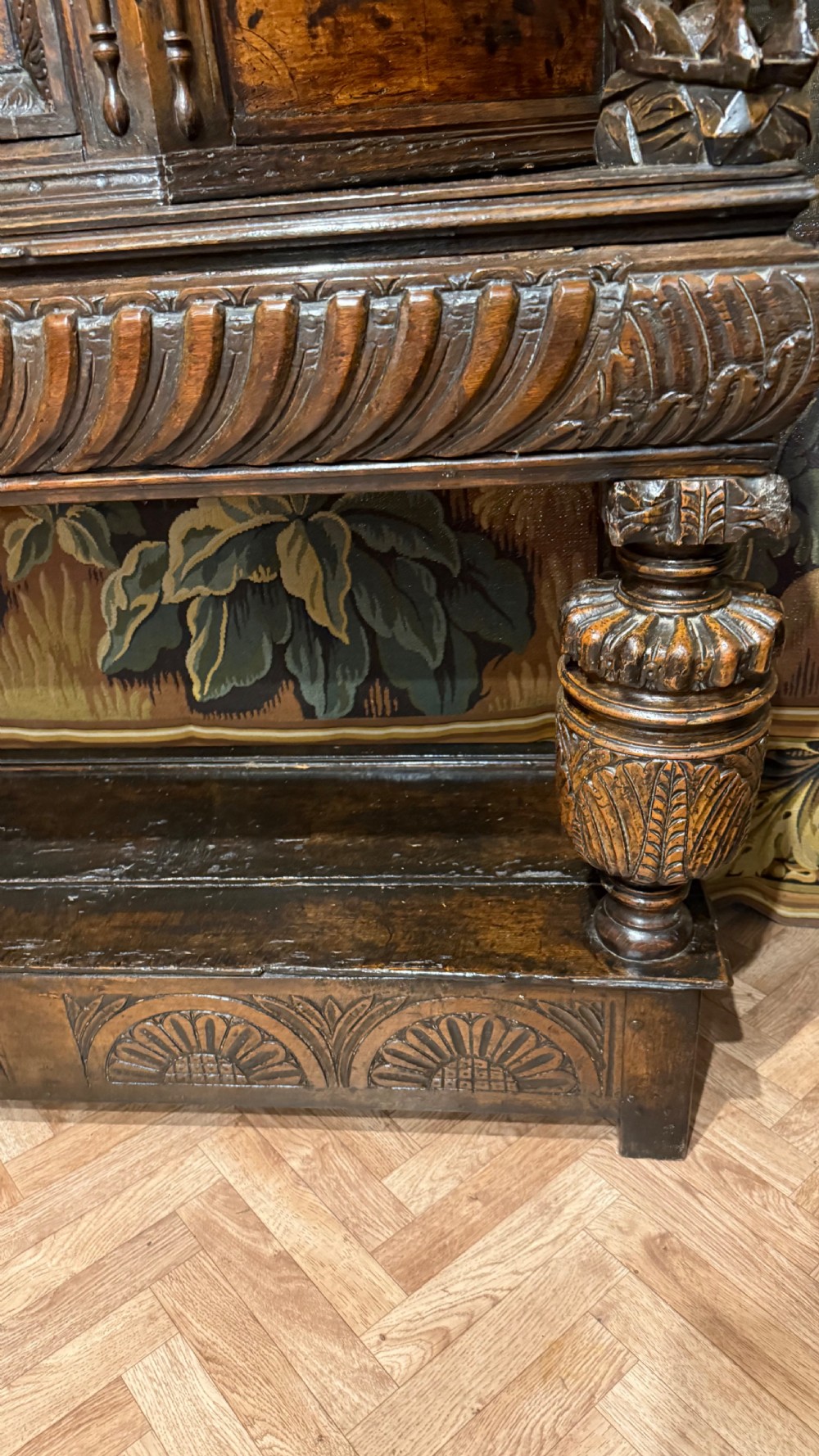 A 17th-century carved oak livery cupboard featuring inlaid wooden panels, carved lion supports, and bulbous turned legs. View VII