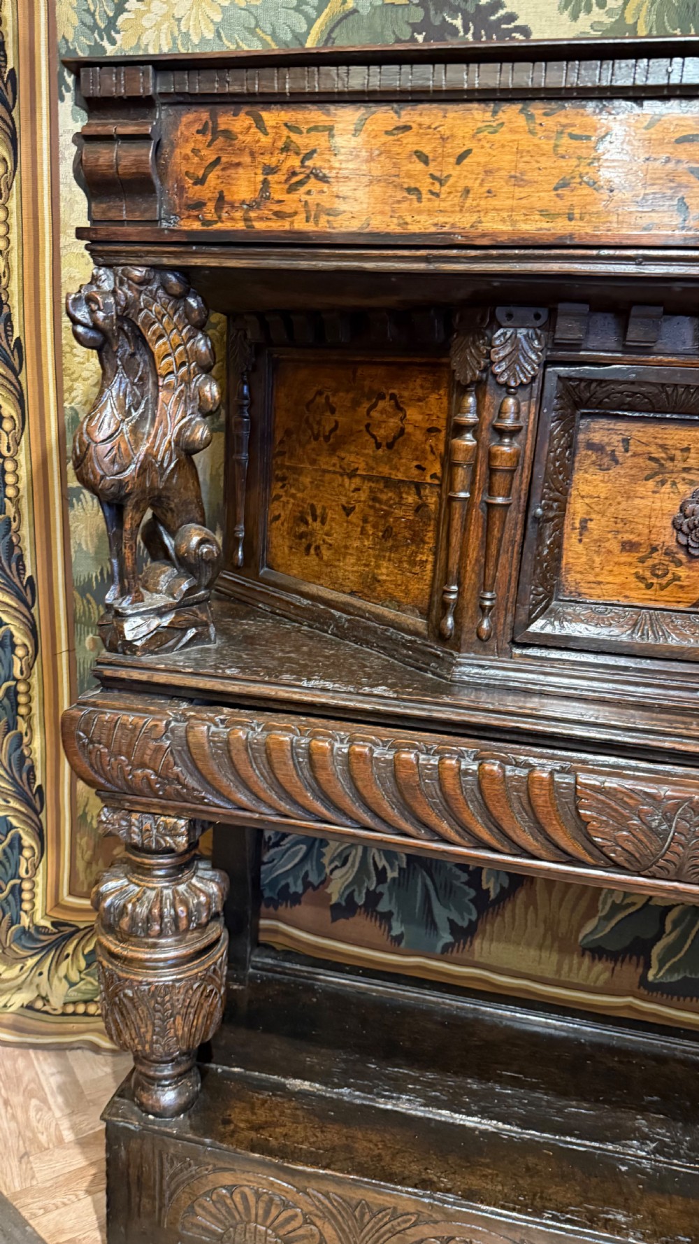 A 17th-century carved oak livery cupboard featuring inlaid wooden panels, carved lion supports, and bulbous turned legs. View VIII