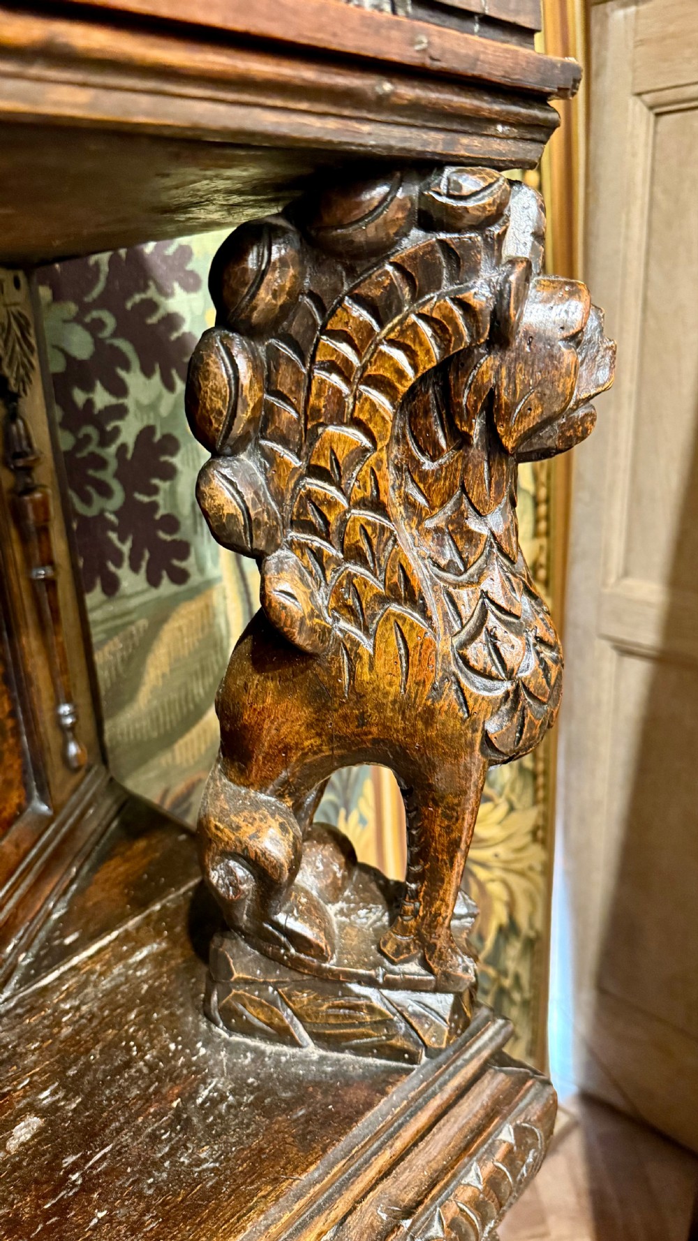 A 17th-century carved oak livery cupboard featuring inlaid wooden panels, carved lion supports, and bulbous turned legs. View X