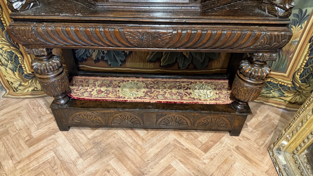 A 17th-century carved oak livery cupboard featuring inlaid wooden panels, carved lion supports, and bulbous turned legs. View XV