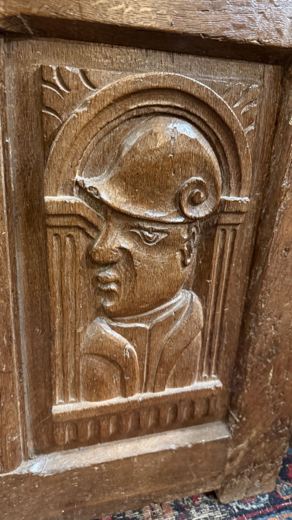 A 16th-century oak coffer featuring two carved Romayne head panels set within carved arches and a central keyhole escutcheon. View III
