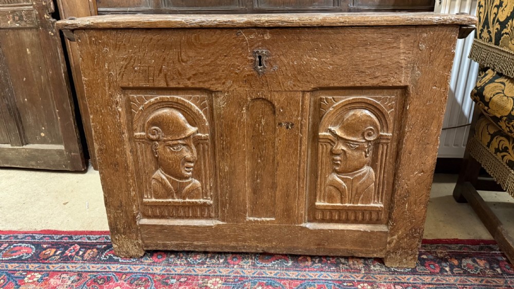A 16th-century oak coffer featuring two carved Romayne head panels set within carved arches and a central keyhole escutcheon. View V