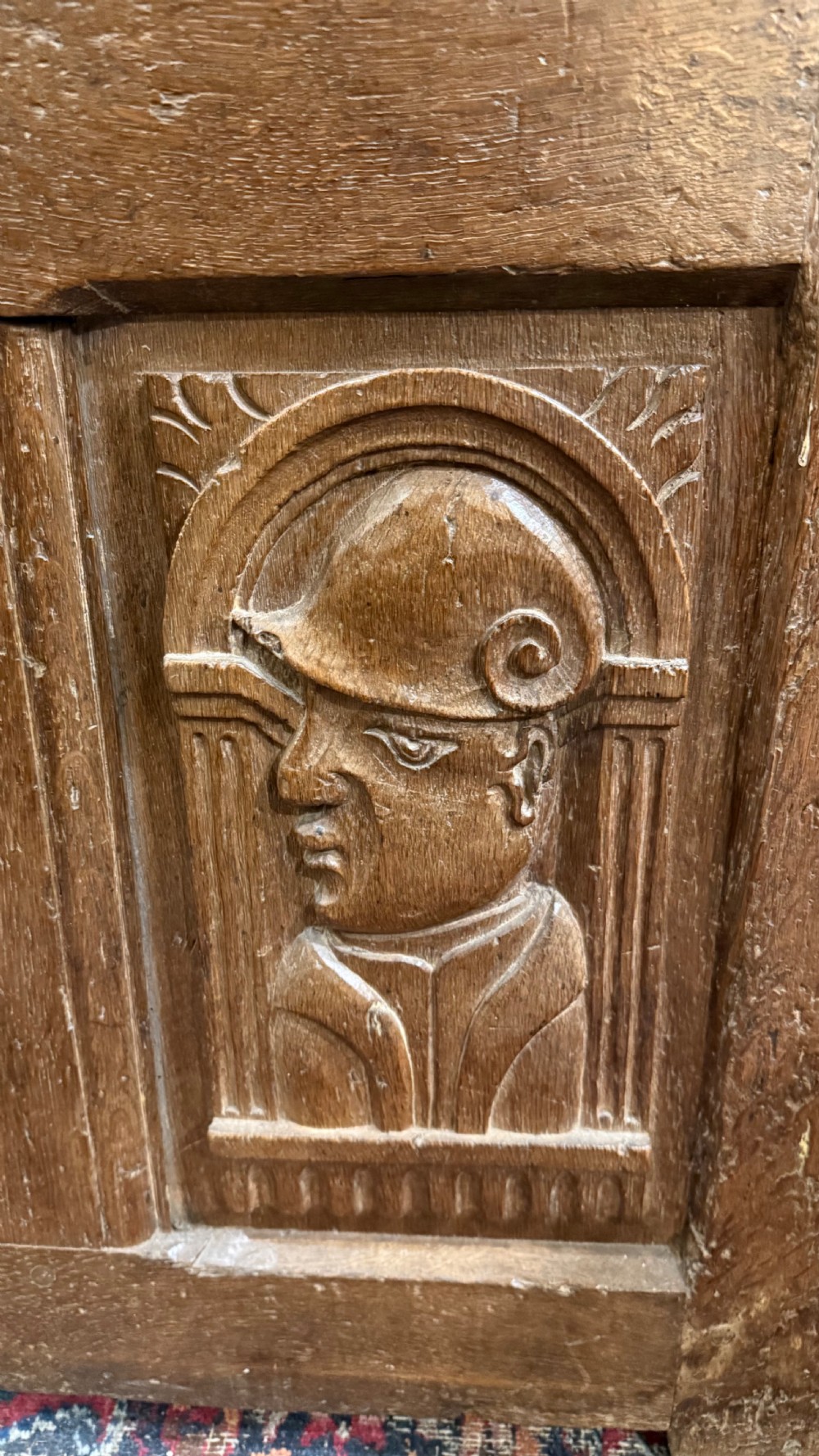 A 16th-century oak coffer featuring two carved Romayne head panels set within carved arches and a central keyhole escutcheon. View VII