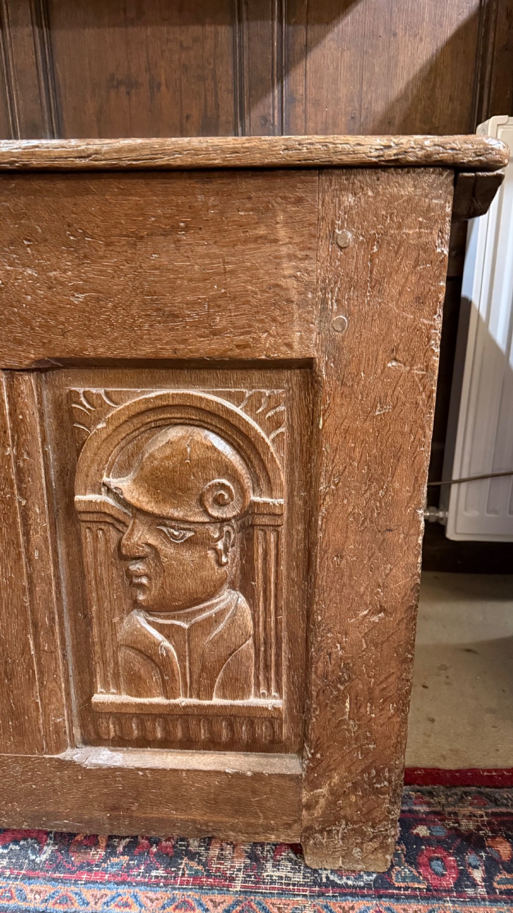 A 16th-century oak coffer featuring two carved Romayne head panels set within carved arches and a central keyhole escutcheon. View XII