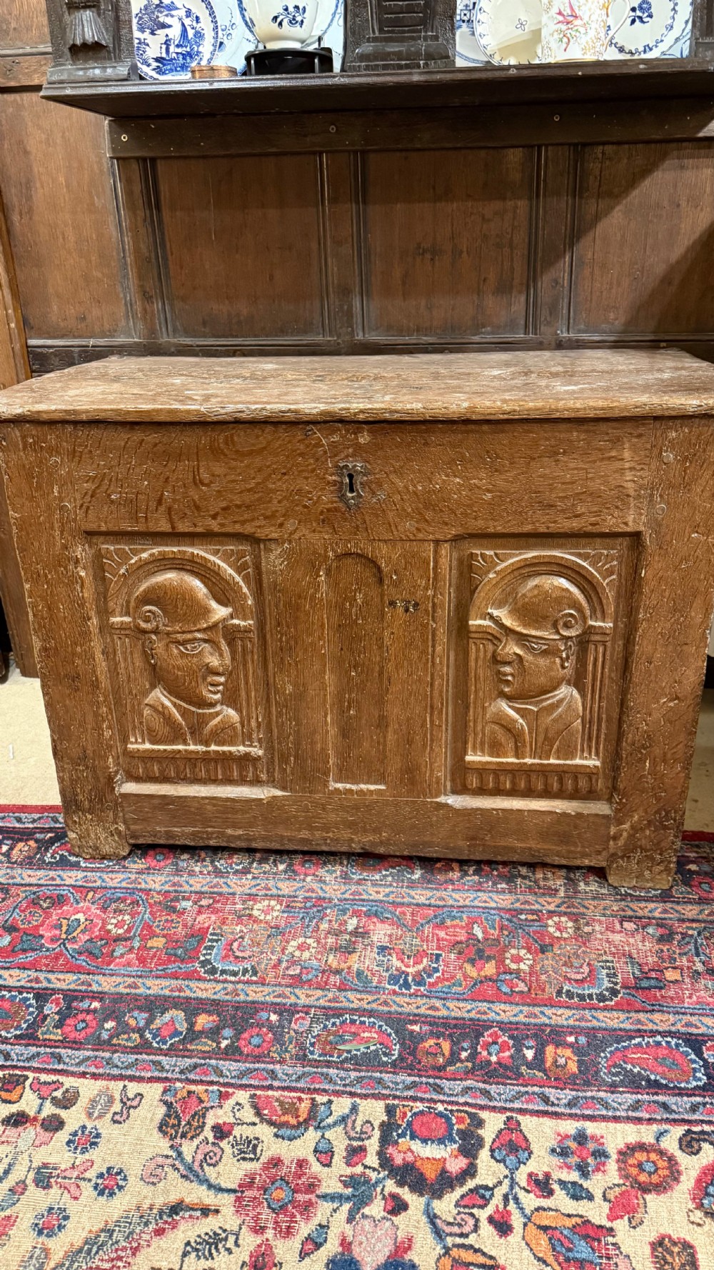 A 16th-century oak coffer featuring two carved Romayne head panels set within carved arches and a central keyhole escutcheon. View XVI