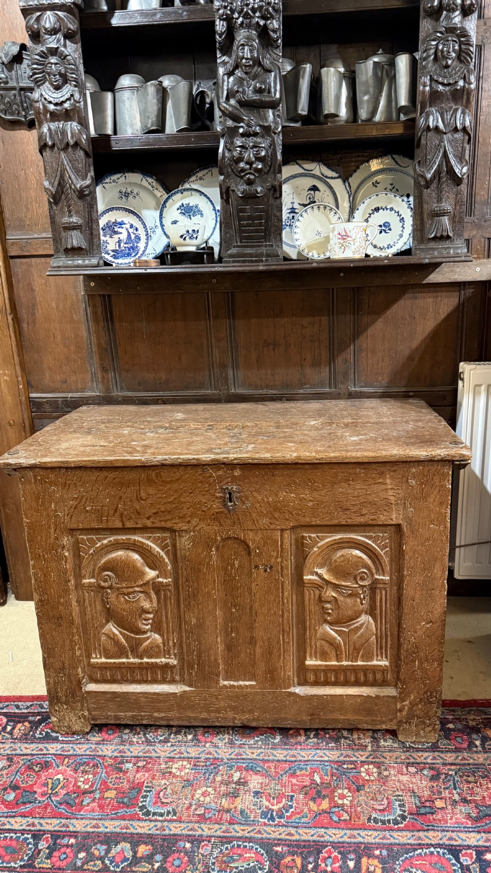 A 16th-century oak coffer featuring two carved Romayne head panels set within carved arches and a central keyhole escutcheon. View XVII